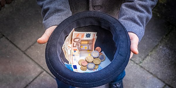 Hands holding a hat to collect money